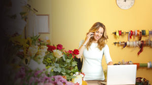 Woman on the phone behind her computer at a flower shop.
