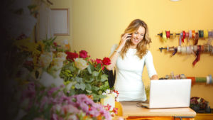 Woman on the phone behind her computer at a flower shop.