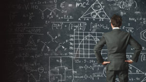 Man looking at chalkboard with complicated equations.