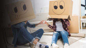 Couple moving in with boxes on their heads.